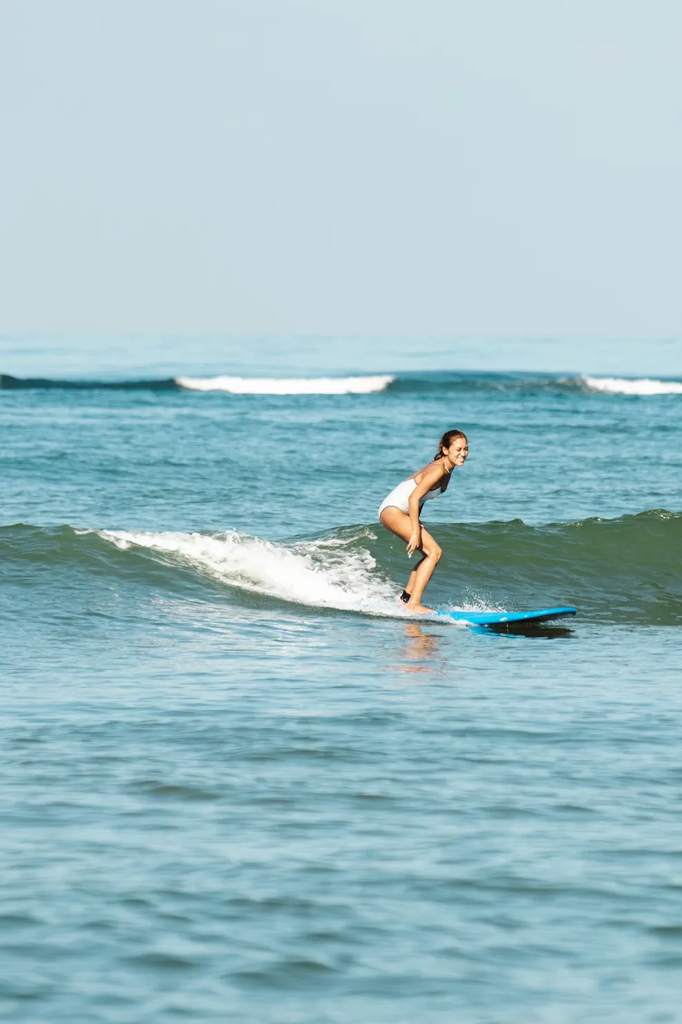 Beginner surfer riding a wave, standing on the board and smiling